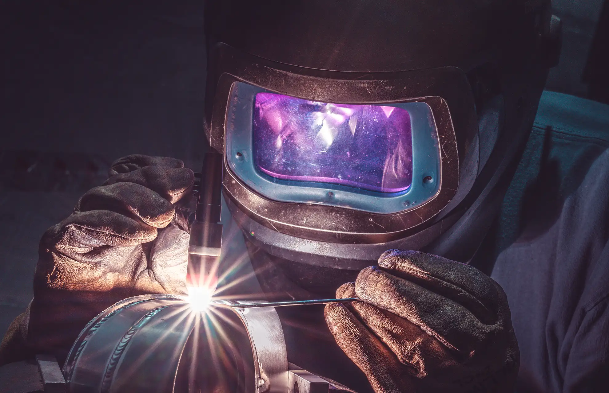 Close-up of TIG welder working on metal pipe for fabrication services